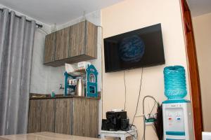a living room with a television and a room with a table at Saagite Apartments in Ongata Rongai 