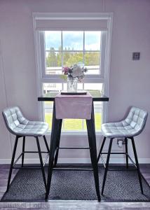 a table with two chairs and a vase with flowers on it at Sunset lodge 32 in West Thirston