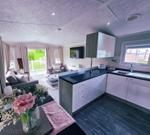 a kitchen with white cabinets and a living room at Sunset lodge 32 in West Thirston