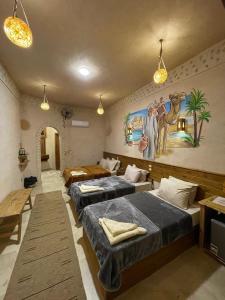 a room with three beds and a painting on the wall at SiwaTu Lodge in Siwa