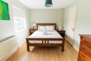 a bedroom with a bed with white sheets and wooden floors at Riverview House - Cahersiveen in Cahersiveen