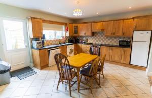 a kitchen with wooden cabinets and a table and chairs at Riverview House - Cahersiveen in Cahersiveen