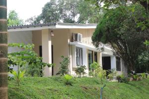 a white house with a tree in front of it at Melani Villa in Kandy