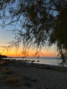 a sunset on a beach with umbrellas and the ocean at Komi Seaside Living in Kómi