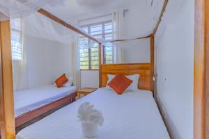 a bedroom with two beds with white sheets and a plant at Solana Pearl Beach Private Villa in Tiwi