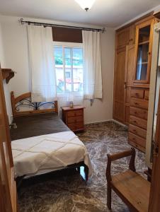 a bedroom with a bed and a dresser and a window at La Casuca in El Pelayo