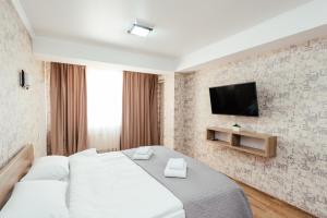 a bedroom with a bed and a tv on a wall at Apart Hotel Anastasia in Chişinău