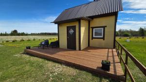 a tiny house with a deck in a field at Peeduland Cabin in Kohatu