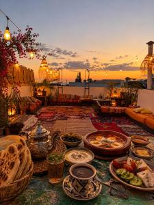 a table with plates of food on it with the sunset at Riad Boya Surf - Lodge in Agadir
