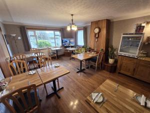 a living room with tables and chairs and a television at Sanderlay Guest House in Kirkwall