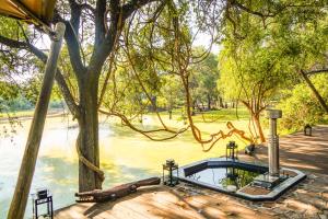a hot tub on a deck next to a tree at Painted Dogs Lagoon in Kakumbi
