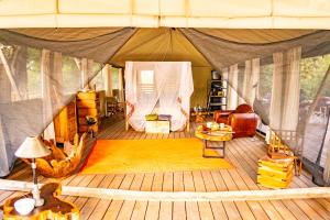 a room with a tent with a couch and chairs at Painted Dogs Lagoon in Kakumbi
