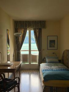 a bedroom with a bed and a table and a window at Seehotel Bären in Brienz