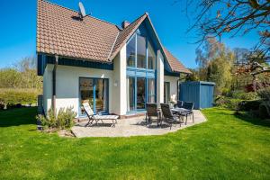 a house with chairs and a table in the yard at Meeresrauschen 1 in Groß Kirr