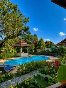 a swimming pool in a yard with a umbrella at Oriental Siam Resort in Chiang Mai