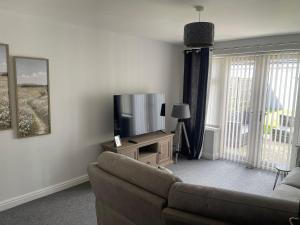 a living room with a couch and a flat screen tv at Modern spacious private detached house in Beeston