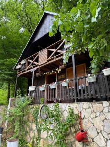 a wooden house with a porch and a stone wall at Vikendica Lenka in Sijarinska Banja
