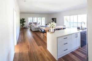 a kitchen and living room with white cabinets and wood floors at Martyr Views in Warburton