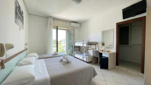 un dormitorio con una cama, un escritorio y una ventana en Hotel Amedea, en Cervia