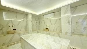 a white bathroom with marble walls and a table at Teker Suite Hotel in Mersin +22 photos