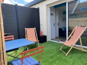 a patio with two chairs and a blue table and a table at Maisonnette de la mer in Hermanville-sur-Mer