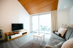 a living room with a couch and a tv at Casa das Ondas in Ribeira Grande