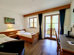 a hotel room with a bed and a desk and windows at Hotel Pfrontener Hof in Pfronten