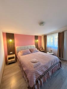 a bedroom with a large bed with a pink wall at Sunset Expanse in Turda