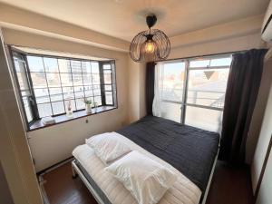 a small bedroom with a bed and two windows at High-speed Wi-Fi Station front Kamishinjo in Osaka