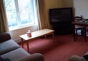 ein Wohnzimmer mit einem Couchtisch und einem TV in der Unterkunft Town Apartments Aberdeen in Aberdeen