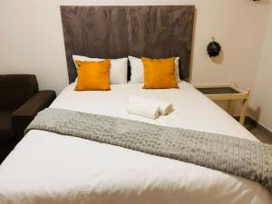 a large bed with orange and white pillows at MandA Cozy GuestHouse in Middelburg