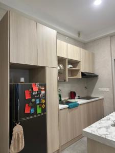 a kitchen with a black refrigerator with magnets on it at ANTARA Muji Serenity Condo in Putrajaya