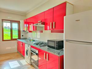 a kitchen with red cabinets and a white refrigerator at Golden Holiday Family Only in Tangier