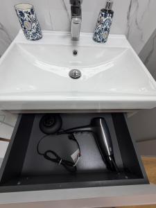 a bathroom sink with a vacuum under it at MG Apartament City Park in Szczecinek +10 photos