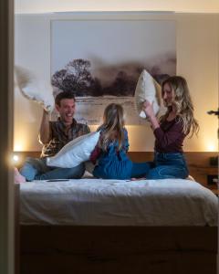 a group of people sitting on a bed with pillows at Lisine Lepo Mesto Guesthouse & Spa in Strmosten