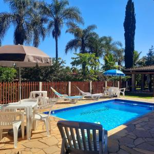 a swimming pool with chairs and umbrellas next to at Chácara Vicente Gazzi in Socorro