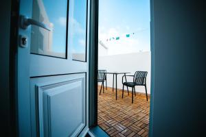 a door leading to a balcony with a table and chairs at Casa do Mar in Ribeira Grande