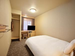 a hotel room with a bed and a television at Dormy Inn Hiroshima in Hiroshima +79 photos