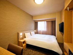 a hotel room with a bed and a window at Dormy Inn Hiroshima in Hiroshima