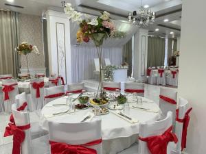 a banquet hall with white tables and chairs with red bows at Hotel KTHELLA in Rrëshen