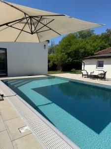 a swimming pool with an umbrella next to a house at House on the river in Karlovac