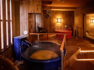a room with a tub with a table and a bench at Dormy Inn Hiroshima in Hiroshima