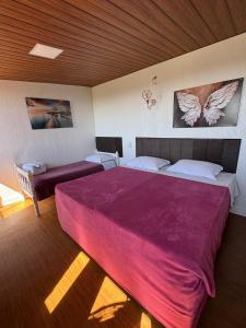 a bedroom with a large bed with a red blanket at Pousada nas Montanhas Recanto Querubins in Paty do Alferes