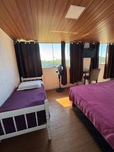 a bedroom with a bed with purple sheets and a window at Pousada nas Montanhas Recanto Querubins in Paty do Alferes