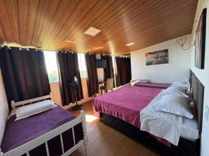 a bedroom with two beds and a wooden ceiling at Pousada nas Montanhas Recanto Querubins in Paty do Alferes