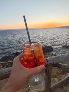 a hand holding a drink in front of the ocean at Sole di Vita in Marina di Strongoli