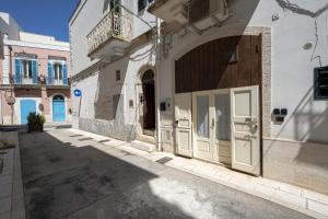 a building with white doors on a street at Casa Tino - Retreat by the Sea and History in Polignano a Mare