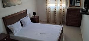 a bedroom with a bed with white sheets and a dresser at Appartement meublé in Constantine