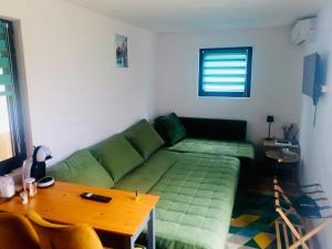 a living room with a green couch and a table at Virajlux in Dâmbovicioara