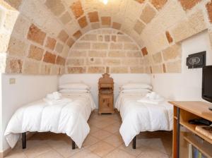 three beds in a room with a stone wall at Casa Tino Panorama Skyline in Polignano a Mare